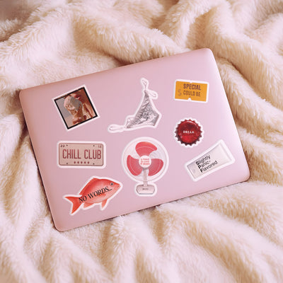 Pink laptop with various stickers on a fluffy white surface