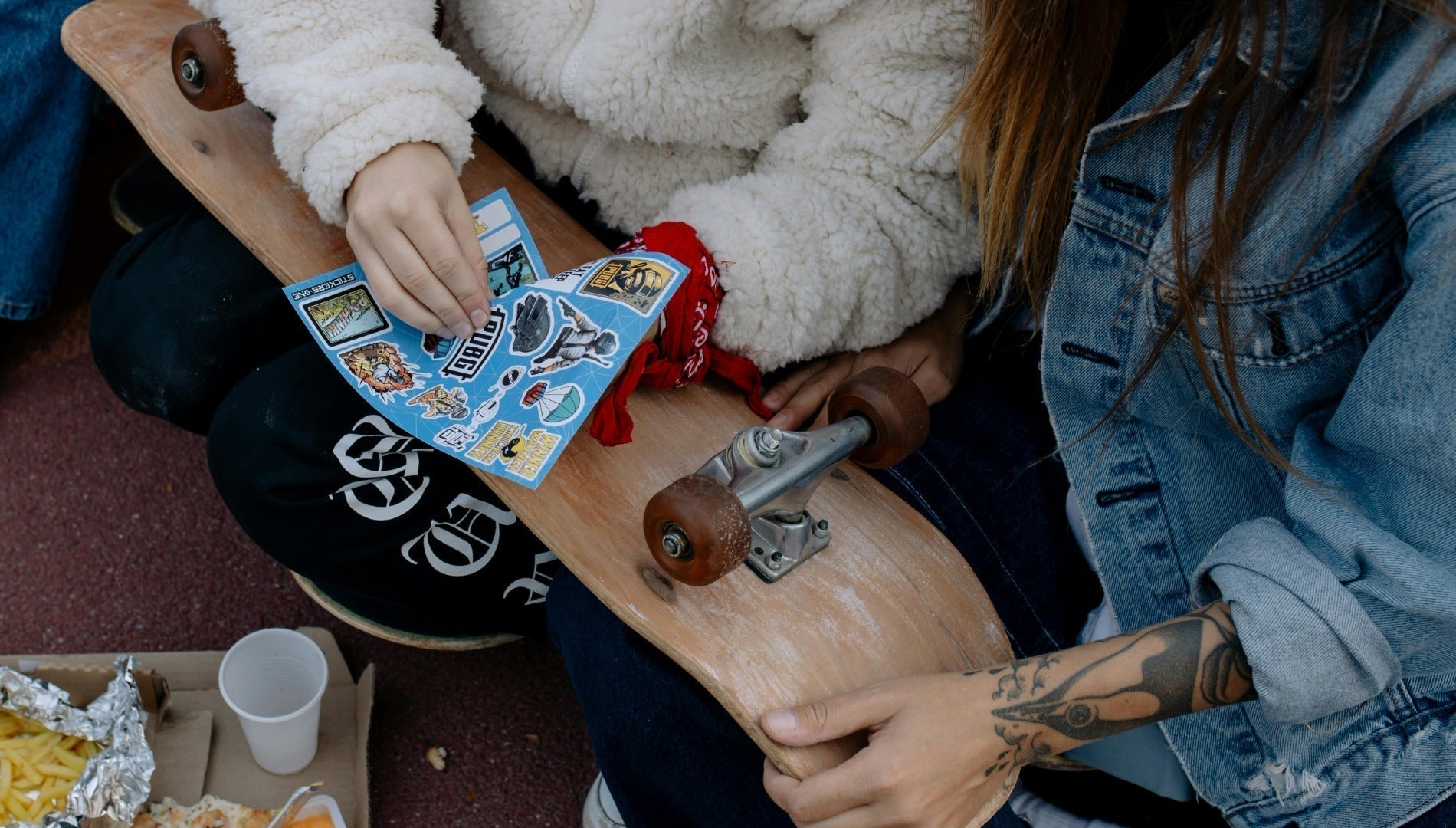 Two girls putting stickers on the skateboard