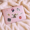 Pink laptop with various stickers on a fluffy white surface